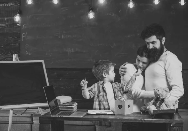 Padres orgullosos viendo el éxito de sus hijos. Concepto de apoyo a padres. Los padres viendo a su hijo dibujar, aprender a escribir, pizarra en el fondo. Niño en la cara ocupada dibujo o escritura . —  Fotos de Stock