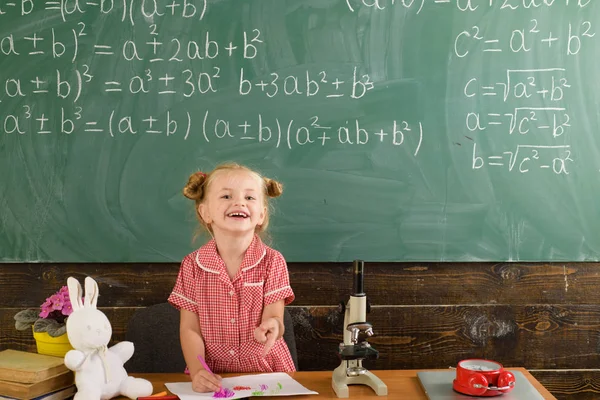 Una studentessa sorride sulla lavagna della classe. Felice studentessa avere lezione nella scuola primaria — Foto Stock