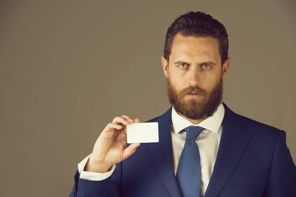 Man holding white business card on grey wall background — Stock Photo, Image