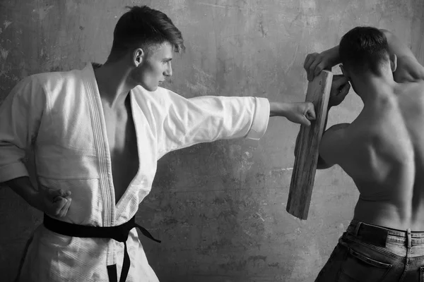 Atleta en kimono blanco perforando tablero de madera —  Fotos de Stock