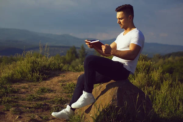 Pensivo homem muscular com livro ao ar livre — Fotografia de Stock