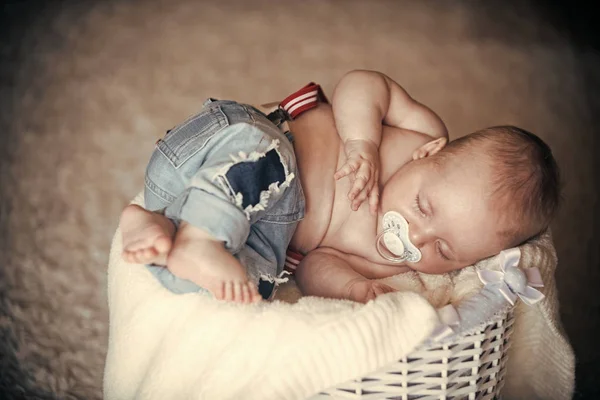 Новорожденный ребенок в джинсах спит в корзине на полу — стоковое фото