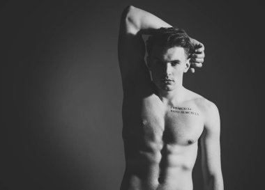 Gövde, altı paketleri, koyu arka plan ile kas maço adam. Adam dövme ile kendinden emin ve çekici görünüyor. Seksi maço kavramı. Maço kas şekil, sporcu, vücut geliştirmeci dalgın yüzünde.