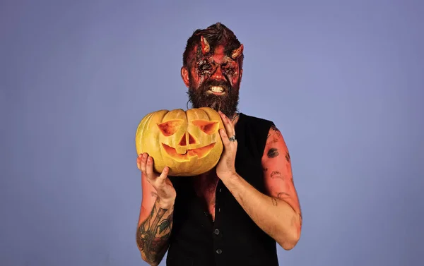 Halloween Mann Teufel hält Kürbis auf blauem Hintergrund — Stockfoto