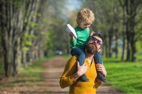 Father and child launch paper plane in park, travel concept. Father and little son plan to travel by plane together. We love to fly — Stock Photo, Image