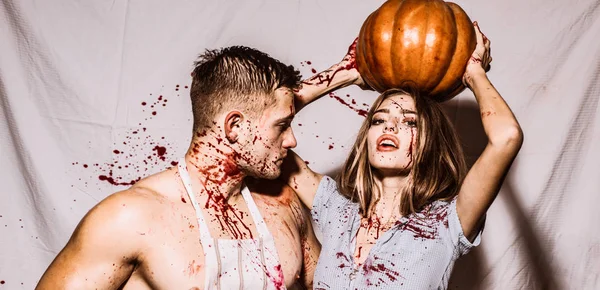 Zombie pár rozhalenou člověka a upíra žena krev a halloween make-up drží dýně, samostatný bílým pozadím. Děsivé zombie pár. Zombie téma. — Stock fotografie