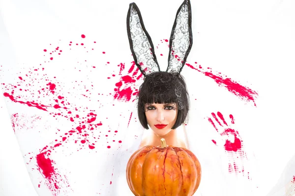 Сексуальная зомби девушка с тыквой на белом кровавом фоне. Красавица в платье кролика с макияжем на Хэллоуин . — стоковое фото