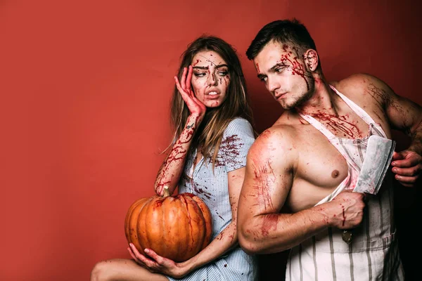 Halloween student party in blood. Couple of muscular man and bloody young woman with wounds and red blood. Terrifying zombie couple