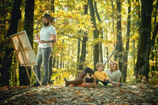Man artist painting autumn picture. Family camping with kids.