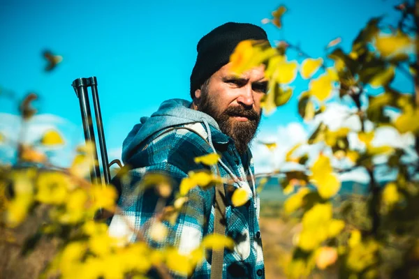Silah tutan ve ormanda yürüyüş sakallı avcı adam. Sınır tanımayan avlar. Hunter avı av tüfeği silah ile. — Stok fotoğraf