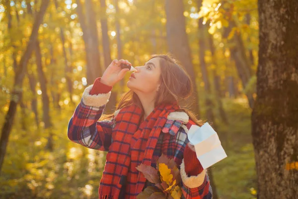 Jeune femme avec essuie-nez près de l'arbre d'automne. Portrait de jeune femme reniflant vaporisateur nasal fermant une narine. Femme présentant des symptômes d'allergie se mouchant . — Photo