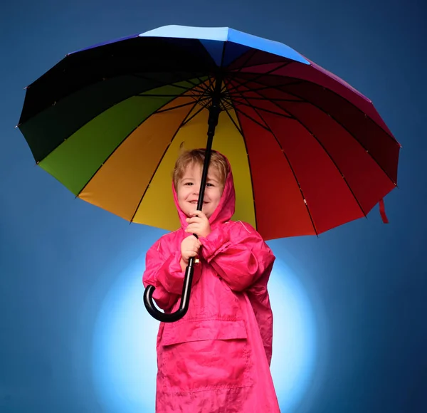 Menino bonito está se preparando para o outono. Miúdo a divertir-se com o Leaf fall. Guarda-chuva de nuvens. Conceito de chuva. Menino alegre em capa de chuva com guarda-chuva colorido. Crianças a chover . — Fotografia de Stock