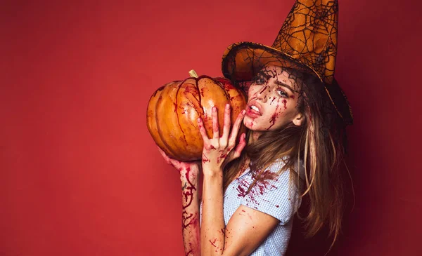 Felice giovane donna costume di Halloween con cappello in piedi su sfondo rosso. Bella giovane donna sorpresa in costume con zucca in mano. Strega di Halloween con zucca . — Foto Stock