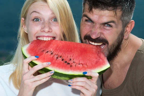 Lyckliga sorglös paret äter vattenmelon. Vitaminer och friska koncept. Njuter en vattenmelon. Par vänner äta en vattenmelon bit och skrattar tillsammans. Holiday. — Stockfoto