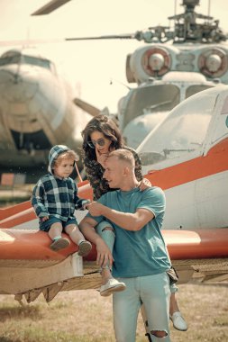 Anne, baba ve heyecanlı çocuk uçak kanat Havacılık Müzesi'nde oturmak. Yetiştirme ve geliştirme kavramı. Mutlu bir aile gezisi, helikopter veya arka plan, uçakta güneşli bir gün.