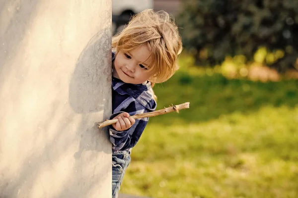 Мальчик с светлыми волосами с улыбкой на углу стены — стоковое фото