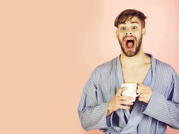 man scared and drinking cup of tea or coffee in robe