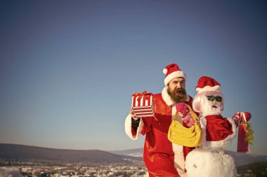 Mutlu Noel Baba adam mevcut kutu mavi gökyüzü üzerinde tutan