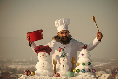 Bağırarak, kardan adam yemek ve xmas ağacı üzerinde mavi gökyüzü kar. Yemek ve diyet kavramı. Noel ve yeni yıl tatilleri gıda. Kaşık ve kırmızı pot tutan adam. Hipster chef şapka ve kış gününde üniforma