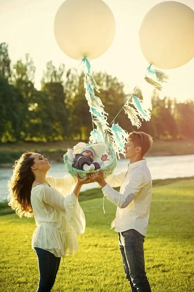 Donna e uomo tengono il bambino nel cestino con palloncini d'aria — Foto Stock