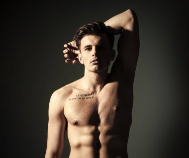 Maço kas şekil, sporcu, vücut geliştirmeci dalgın yüzünde. Gövde, altı paketleri, koyu arka plan ile kas maço adam. Adam dövme ile kendinden emin ve çekici görünüyor. Seksi maço kavramı.