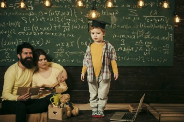 Lisansüstü şapkalı akıllı çocuk gibi gerçekleştirmek. Kitap kara tahta arka plan ile hataları kontrol onların oğlu, dinleme anne. Sınav kavramı için hazırlanıyor. Çocuk Anne ve baba için onun bilgi sunma.