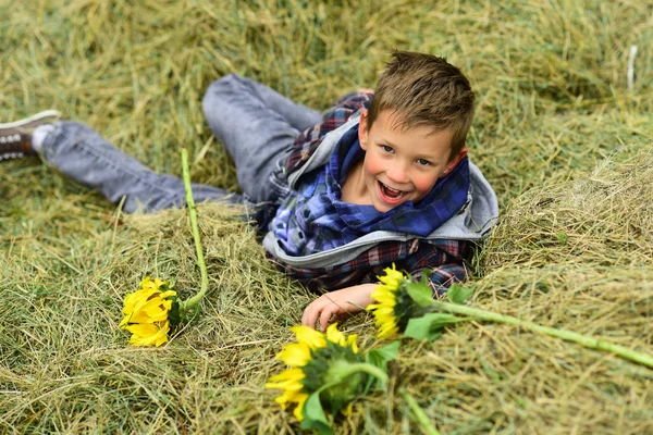 Lycklig barndom tid. Lycklig pojke. Liten pojke glada leende i hö. Lilla barn på gården. Play är ett verk av barndomen — Stockfoto