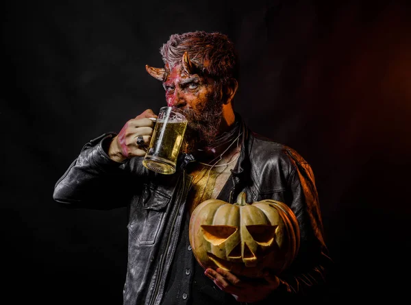 Halloween man with satan horns hold pumpkin