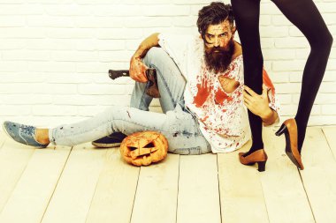 Ahşap zemin üzerinde kadın ince bacakları yakınındaki sakal vampir adamla sakallı zombi veya yaralar olan kanlı savaş asker ve Cadılar Bayramı Balkabağı ve balta ile kırmızı kan oturur.