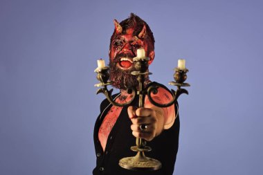 Cadılar Bayramı adam şeytan şamdan mavi arka plan üzerinde tutan