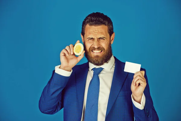 Человек с кислым лимонным фруктом, держащий бизнес или кредитную карту — стоковое фото