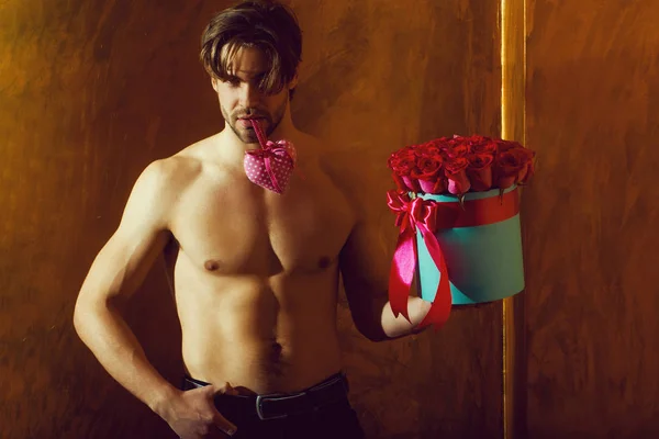 Svalnatý vousáč s sexy tělo drží červená růže box — Stock fotografie