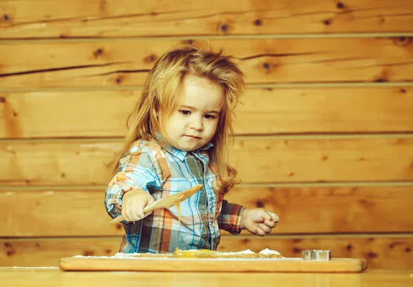 Милый ребенок приготовления пищи с тестом, мука держит дрова лопаты — стоковое фото