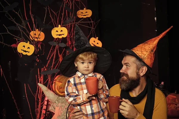 halloween man with child in witch hat drink milk