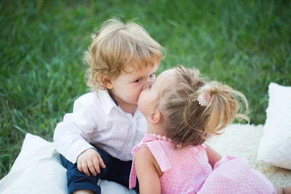 Ragazza bacio ragazzo con i capelli biondi su erba verde — Foto Stock