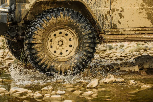 Caminhão esporte off-road entre montanhas paisagem. Vista inferior para grande roda offroad carro no país estrada e montanhas pano de fundo. Trekking de viagem 4x4 . — Fotografia de Stock