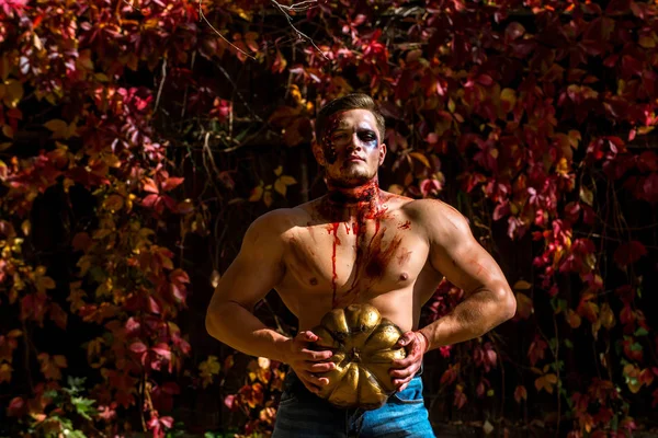 Grande homem zumbi vampiro halloween ou soldado de guerra sangrento com feridas e sangue vermelho com abóbora. 31 de outubro. O crânio compõe o retrato do jovem. Maquiagem e conceito assustador para o homem. Festa de celebração . — Fotografia de Stock