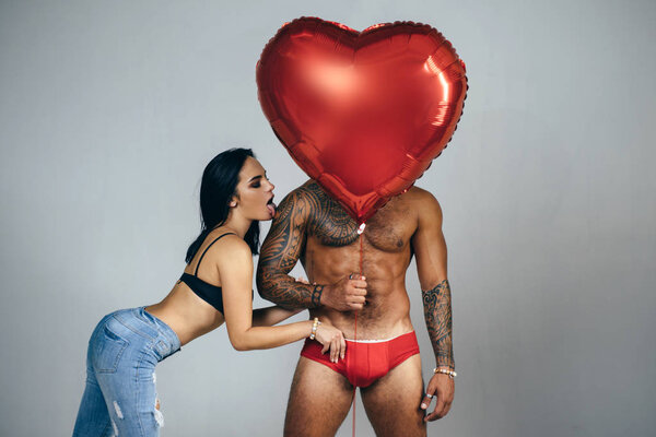 Man in red panties and women with a red heart balloon - Valentine symbol. Lover and heart attack. Couple in love. St Valentines Day concept.