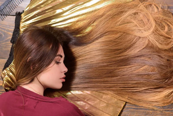 Cabello largo sobre fondo de madera. Cosméticos para el cabello, cuidado del cabello. Retrato de una joven con cabello largo y saludable . — Foto de Stock