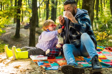 Baba ve oğul sonbahar ormanda oynuyor. Burun silecek Park sarı ağaçları arasında genç çocukla hapşırma. Baba ve çocuk evlat gülen ve having fun Sonbahar Park.