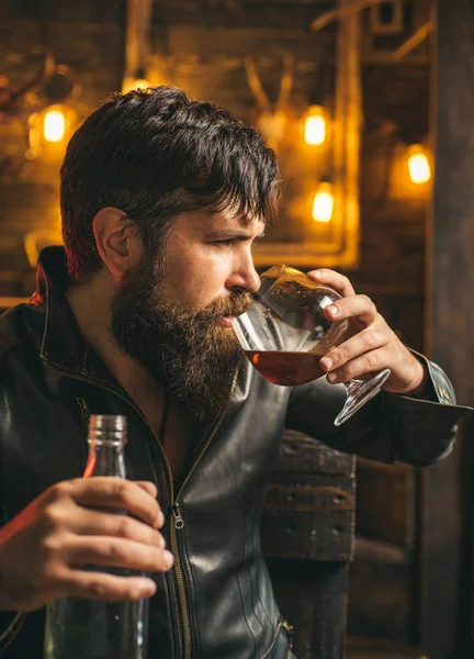 Muž pije brandy nebo whisky. Vousatý muž v bundě a pije whisky brandy nebo koňak. Vážný muž s alkoholem a závislostí na nikotinu. Zastavte alkohol a kouření závislost. — Stock fotografie