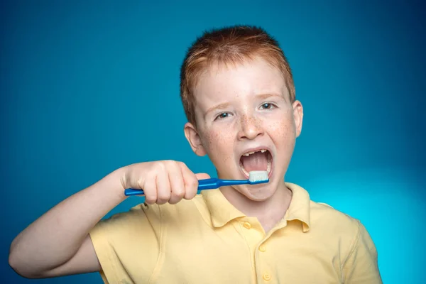 Boy is brushing his teeth. Happy child kid boy brushing teeth. Smiley boy without one teeth with toothbrush isolated on blue background. Shirt design, health, oral hygiene. — Stock Photo, Image