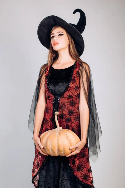 Elegant charming shy playful flirty dangerous mysterious scary female beauty. Beauty Woman posing with Pumpkin and Halloween hat. Attractive model girl in Halloween costume. Halloween concept. — Stock Photo, Image