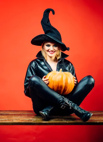 Bruxa posando com abóbora. Jovem gótica feliz em traje de bruxa halloween. Conceito de Halloween . — Fotografia de Stock