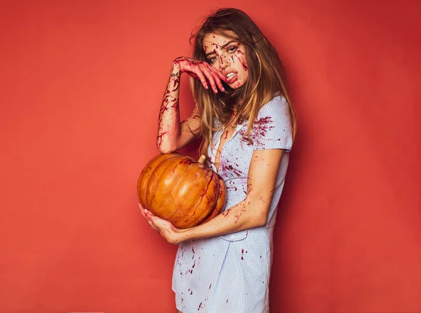 Sukienka sexy girl killer do festiwalu Halloween. Halloween dziewczyna z rzeźbione dyni. Dość młoda blond kobieta odziany w strój z dyni. Seksowny Wampir kobieta z krwi na jej twarzy. — Zdjęcie stockowe