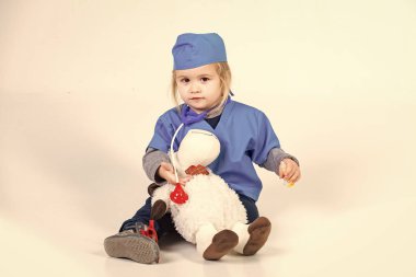 Doktor veteriner oyuncak hayvan ile oynarken üniforma içinde küçük çocuk