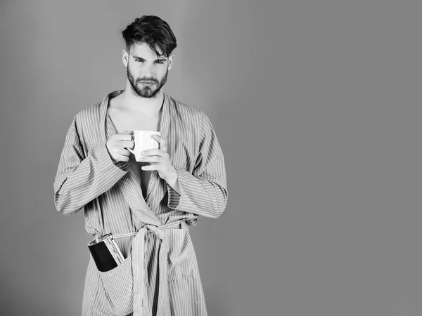 macho in blue robe holding cup and magazine