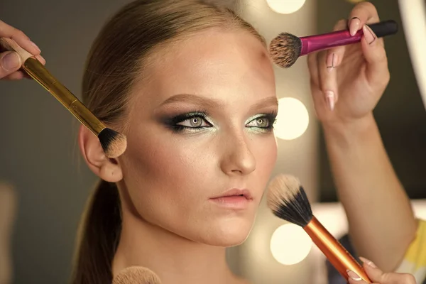 Många händer gör makeup till ung kvinna. — Stockfoto