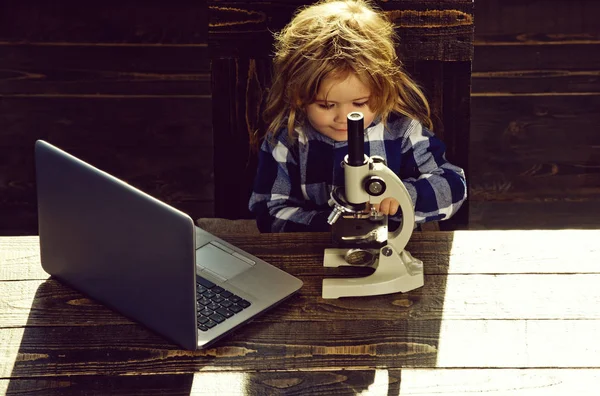 Concepto educativo, niño estudiante que estudia en el lugar de trabajo con microscopio, computadora portátil — Foto de Stock