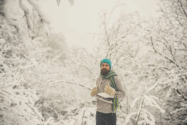 雪に覆われた森でスケートを持つひげを生やした男. — ストック写真